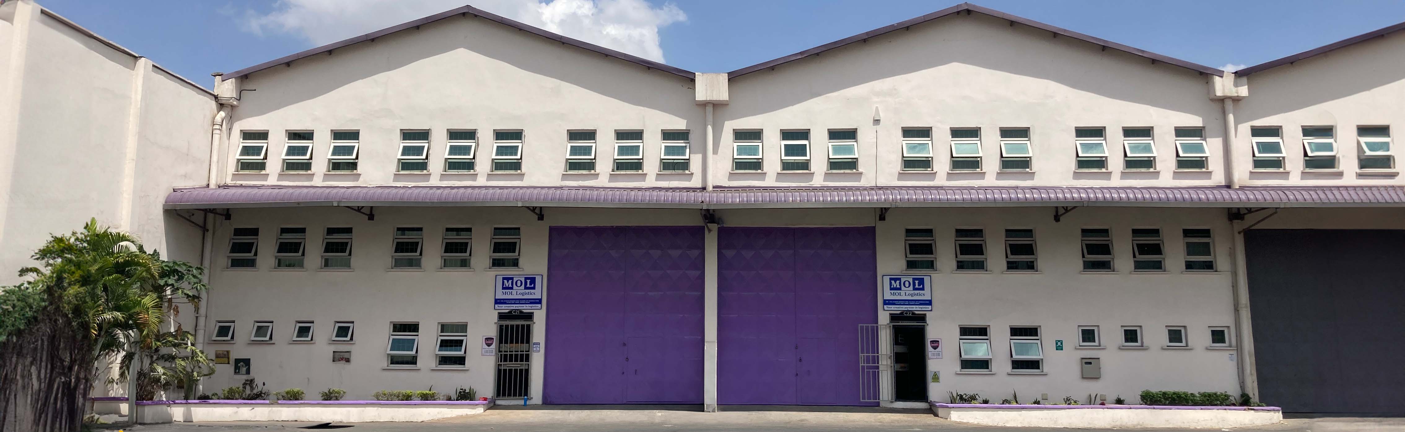 The front view of an MOL Logistics warehouse with purple doors and windows, set against a clear sky, representing the company’s operations in Africa.