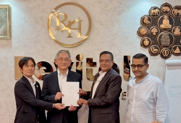 Four men, including two in suits, stand together holding a signed document in front of a Revital Healthcare logo, marking a partnership agreement with MOL.