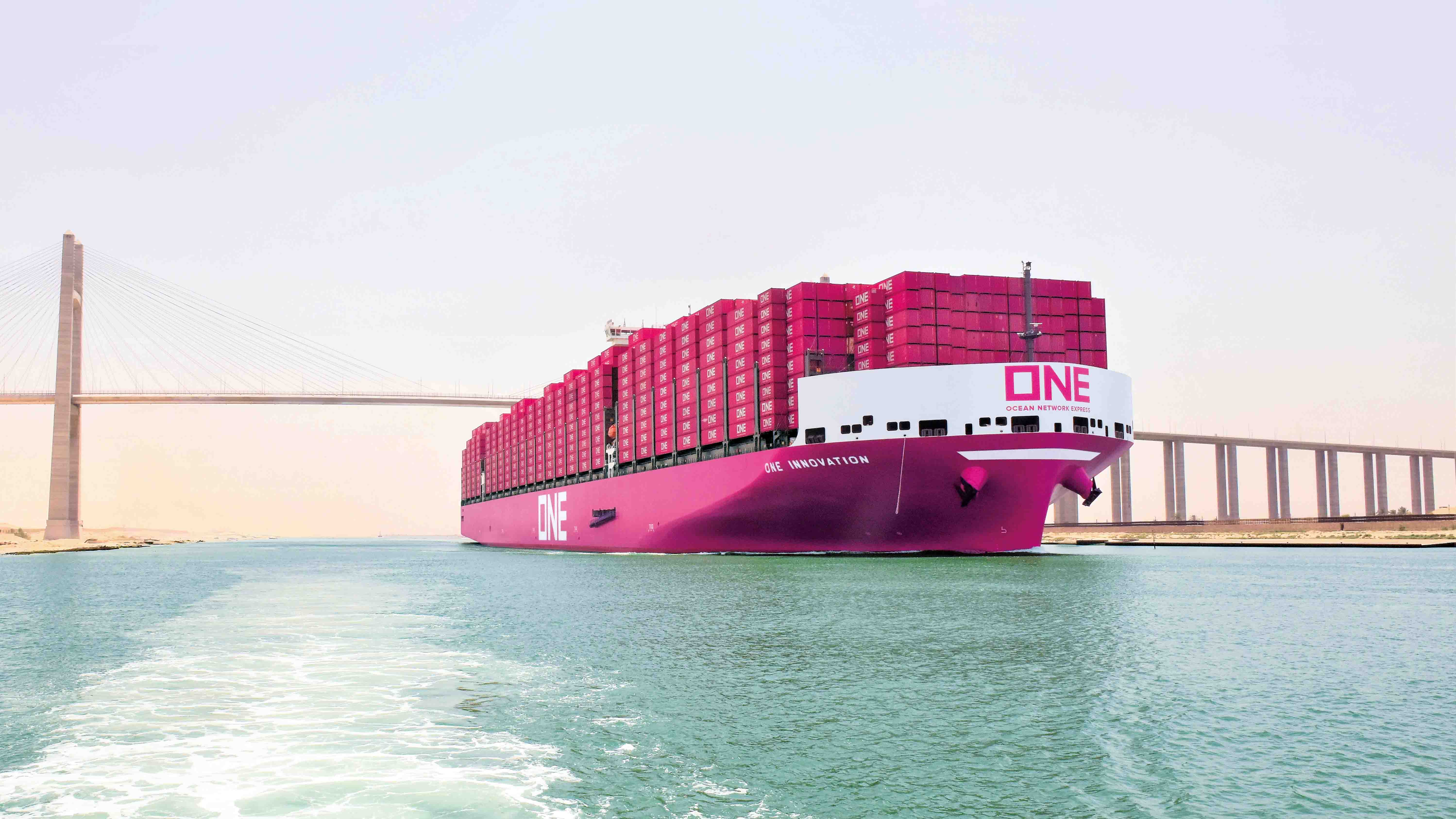 The bright pink ‘ONE Innovation’ container ship is, showcasing the large-scale container transport operations under a clear sky.